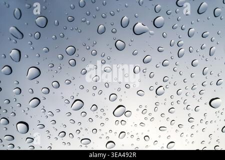 Raindrops on the glass look up to the sky blurred in the background. Stock Photo
