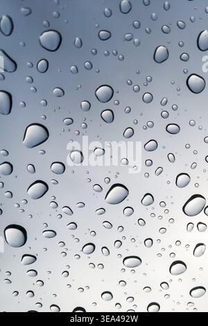 Raindrops on the glass look up to the sky blurred in the background. Stock Photo