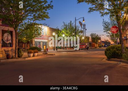 A vintage red flatbed truck parked at Standin' on the Corner Park along historic Route 66 at dusk in Winslow, Arizona. Stock Photo