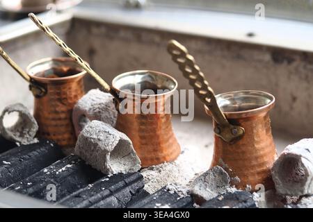 Making turkish coffee with copper pots on hot coals in a kitchen Stock Photo