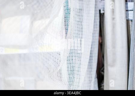 Designer background made of natural light-colored knitted curtain samples with pleats Stock Photo