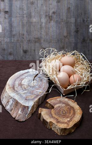 Chicken eggs and two wooden slices on a brown table Stock Photo
