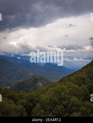 Layered mountain ridges fading into mist beneath dramatic clouds creating an atmospheric landscape scene. Stock Photo