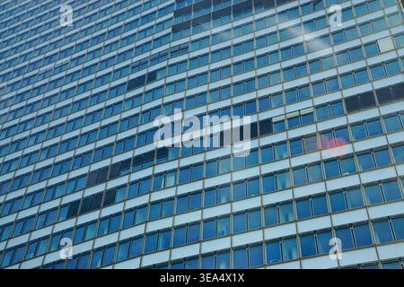 Modern office building facade with repetitive glass windows and metal grid structure viewed in daylight in Vienna, showing geometric pattern and refle Stock Photo