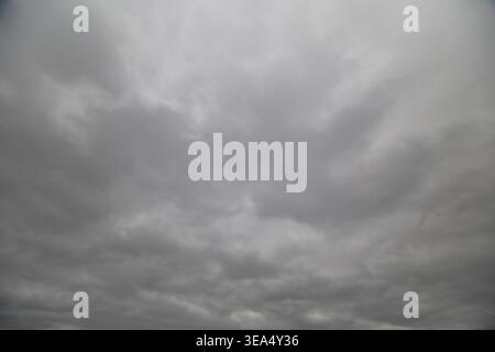 Dramatic cloudy sky before storm, heavy cloud banks and deep gray gradients, turbulent textures suggesting incoming weather, high tension for forecast Stock Photo