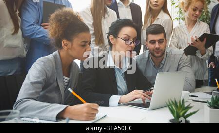 Serious business team analyzing reports on laptop Stock Photo