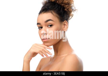 Young Woman Poses in Studio Light With Hand on Chin and Thoughtful Expression Stock Photo