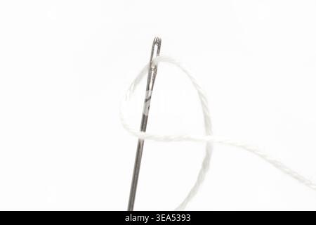 Close-Up of Thread and Sewing Needle on White Background, Minimal Tailoring and Craft Concept Stock Photo