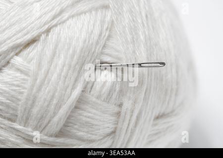 Sewing Needle with White Wool Yarn, Close-Up on White Background Stock Photo