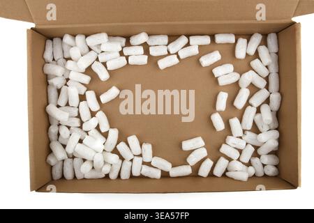 Styrofoam packing peanuts in cardboard box isolated in on white background. White plastic foam pellets protective for parcel packing. Stock Photo