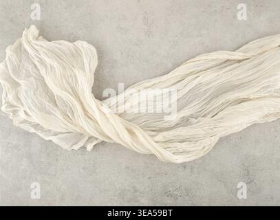 Wrinkled gauze fabric on light grunge stone background. Cotton gauze fabric cloth on stone tile surface with copy space. Stock Photo