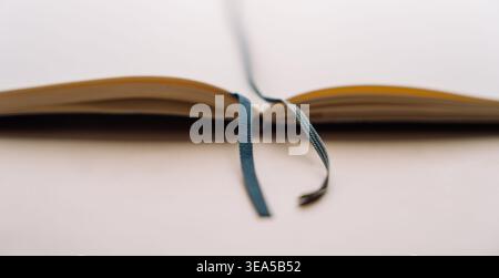 Open dot grid notebook with ribbon bookmark on beige background Stock Photo