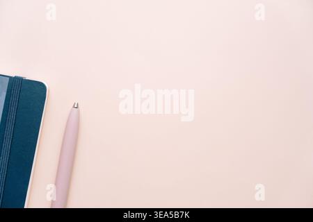 Blue notebook and pink pen on soft beige background Stock Photo