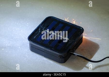 Solar light device on surface sparking as concept of electrical short circuit danger. Stock Photo