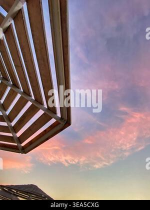 Minimalist architectural structure against soft pastel sunset sky with pink clouds. Stock Photo