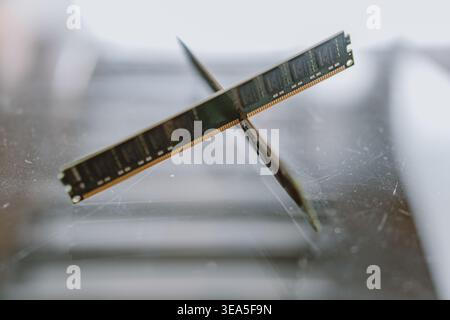 Crossed RAM modules resting on scratched glass surface, close-up tech hardware composition with Stock Photo