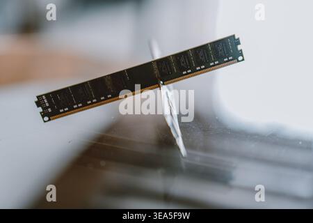 A close-up of a floating DDR4 RAM module balanced on a sharp white blade against a blurred modern Stock Photo