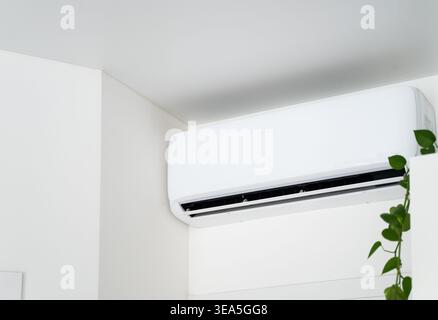 White split air conditioner unit mounted on a wall, providing cooling and comfort in a modern indoor space Stock Photo