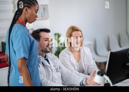 Medical professionals collaborating on computer while discussing patient information Stock Photo