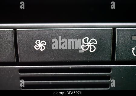 Macro close up of black car dashboard buttons with white fan speed propeller icons for climate control ventilation Stock Photo