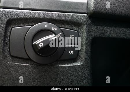 Close up of a modern car headlight control switch dial and fog light buttons on a black textured dashboard Stock Photo