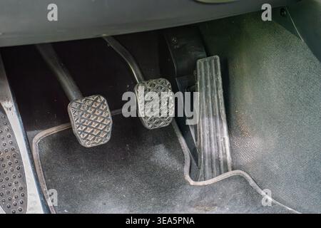Close up of manual transmission car pedals featuring the clutch brake and gas pedal on a dark floor mat Stock Photo