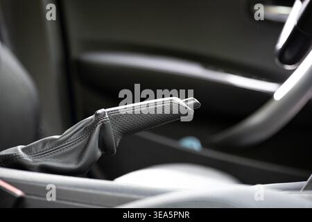 Close up of a black leather manual handbrake lever in a modern car interior with perforated grip texture Stock Photo