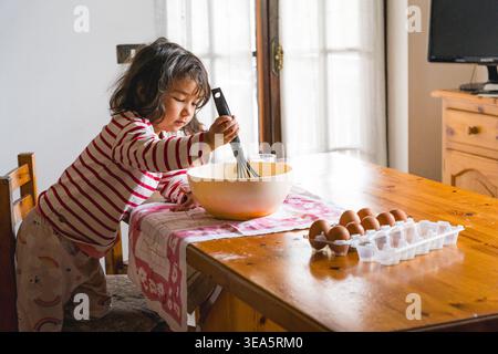 littl toddler girl baking at home in the kitchen with flour, concept activity with children, cooking together with complicity Stock Photo