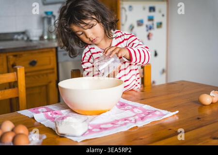 littl toddler girl baking at home in the kitchen with flour, concept activity with children, cooking together with complicity Stock Photo