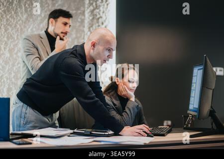 Business team collaborating at computer in modern office discussing project on desktop screen Stock Photo