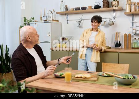 Loving senior couple shares a joyful breakfast, savoring each others company and delicious food. Stock Photo