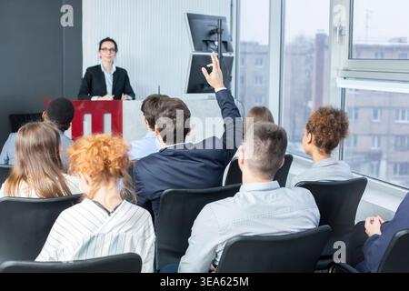 Businessman raising hand at seminar, having question to speaker Stock Photo
