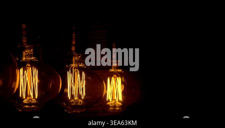 Light bulbs glow in dark space showing warm tones and patterns created by filament during evening hours while resting on surface Stock Photo