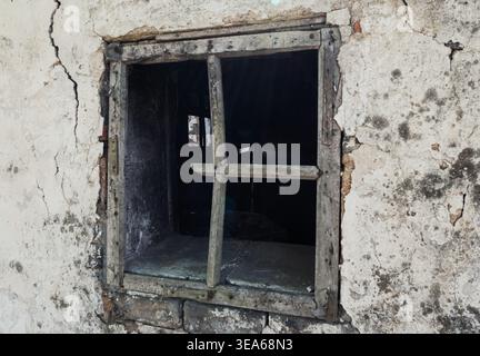 Decaying wooden window frame in a severely cracked and stained wall of an neglected building Stock Photo