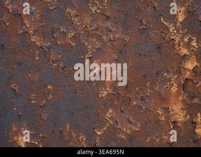 Detailed view of a heavily corroded metal surface featuring peeling layers of rich brown and dark orange rust Stock Photo