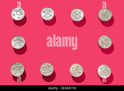 Top view of metal tin cans arranged in a rectangular frame on bright pink background Stock Photo