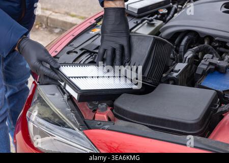 Hands replacing engine air filter in car showing maintenance and repair process close up Stock Photo