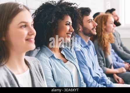 Diverse millennial group sitting in row, waiting for something Stock Photo
