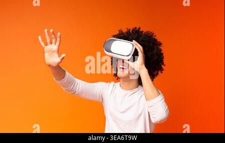 Excited black guy pushing virtual button in VR glasses Stock Photo