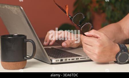 Businessman Working on Laptop With Coffee and Glasses at Home Office Desk, Typing and Focusing Stock Photo