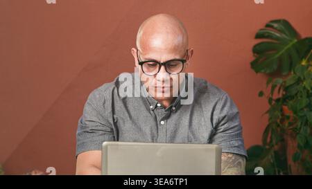 Focused Man Working On Laptop In Casual Office Setting Concentrating On Remote Business Tasks Stock Photo