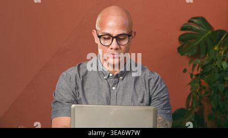 Bald Man With Glasses Working On Laptop In Stylish Home Office Remote Work Setup Stock Photo