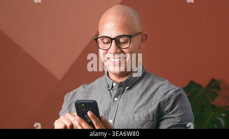 Smiling Professional Man Using Smartphone for Business Communication and Remote Work in Modern Office Stock Photo
