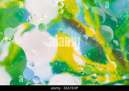 Abstract background of colorful oil drops and water bubbles in vibrant green yellow and blue shades Stock Photo