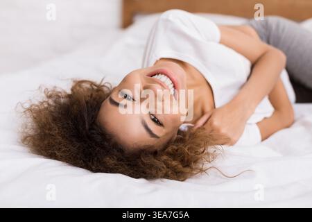 Happy woman lying on bed and looking at camera Stock Photo