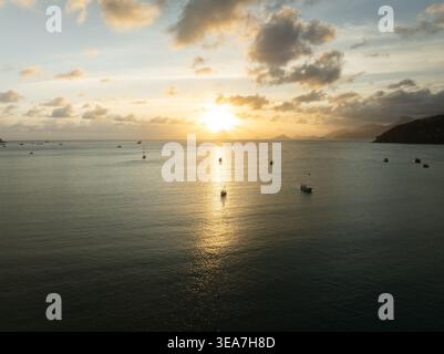 Aerial view of Anse A La Mouche bay with boats anchored on calm waters under a golden sunset sky in Seychelles. Stock Photo