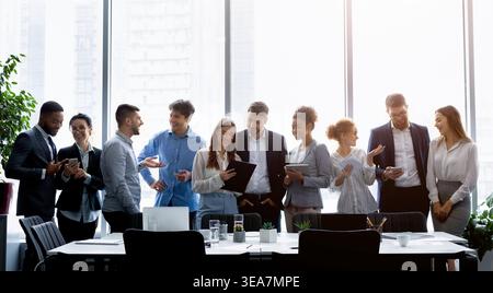 Business people standing against window, discussing work Stock Photo