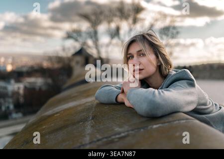 Young Woman Resting on Stone Railing in Soft Outdoor Portrait Stock Photo