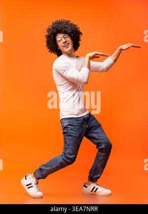 Funny black guy dancing in egypt style on orange background Stock Photo