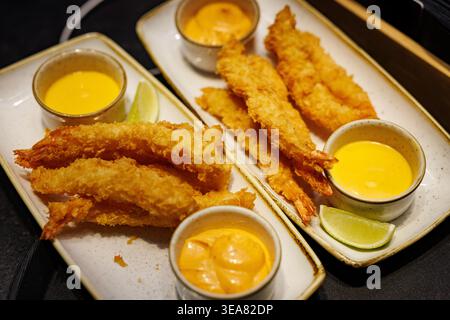 Crispy tempura shrimp with dipping sauces and lime wedges Stock Photo